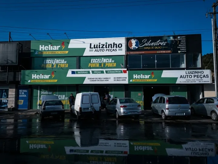 Vista geral de obra de pintura predial com iluminação dramática lateral — equipe em ação com equipamentos industriais