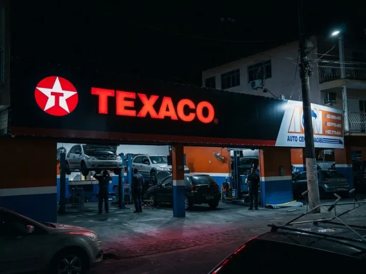 Fachada com letreiro frontlight noturno em posto de combustível — auto center com oficina iluminada